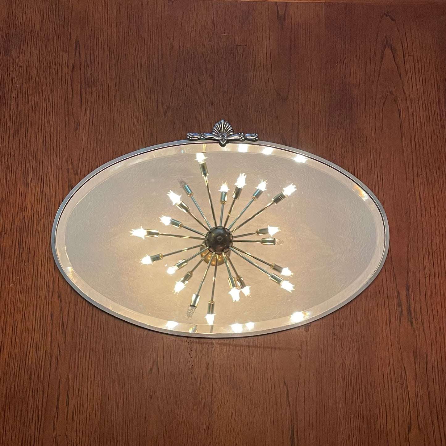 Art Deco beveled mirror with metal frame and decorative topper