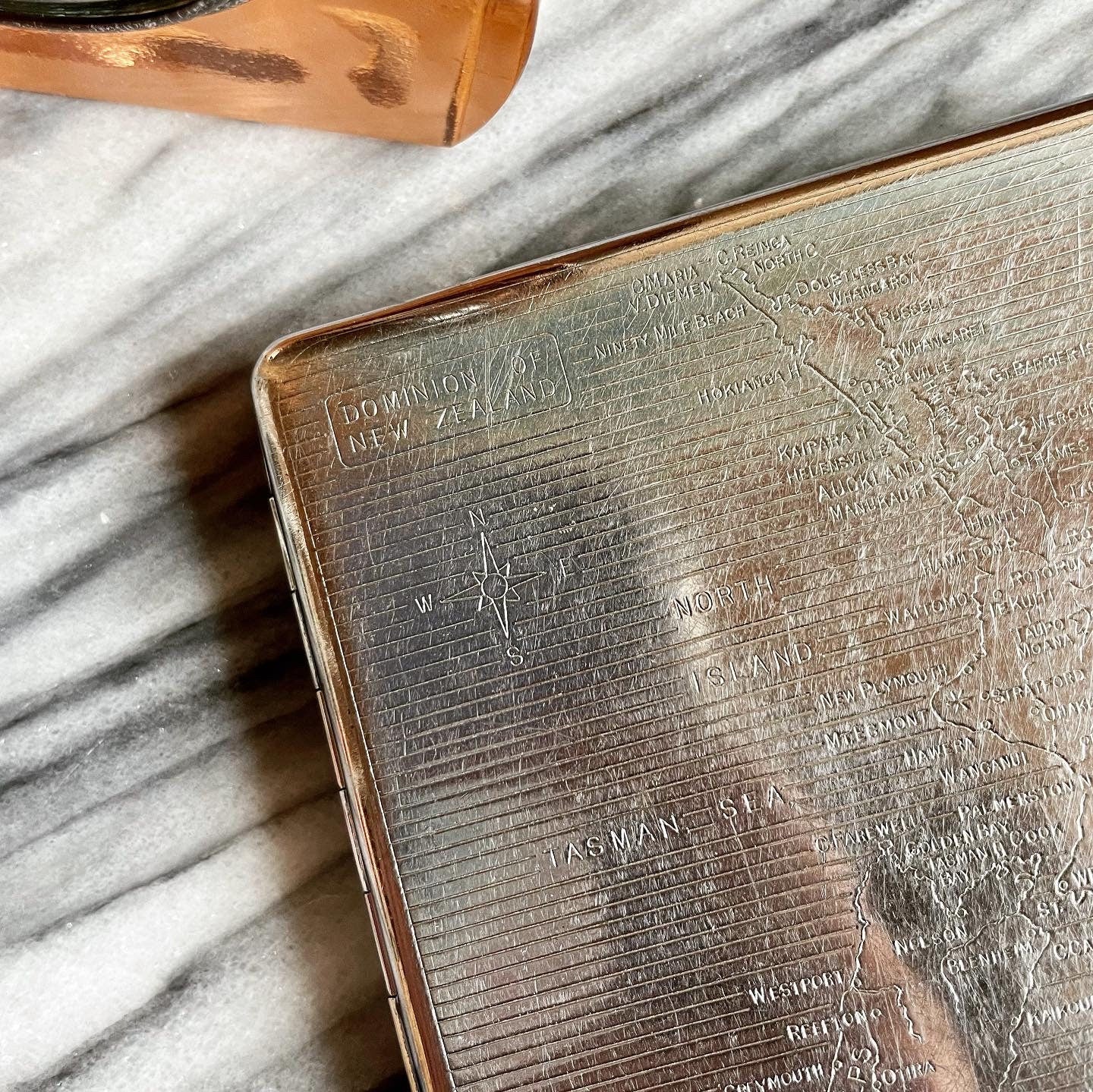 Antique metal cigarette case with map of New Zealand engraved on front