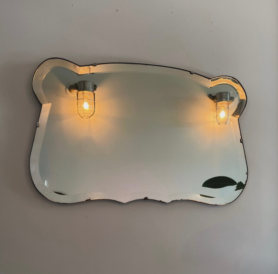 Antique 1930s Art Deco mirror with curving shape and thick beveled edges
