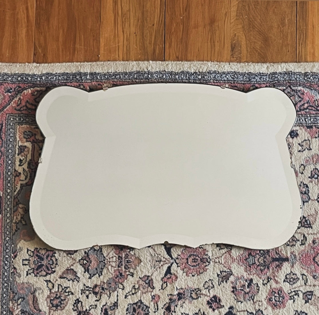 Antique 1930s Art Deco mirror with curving shape and thick beveled edges