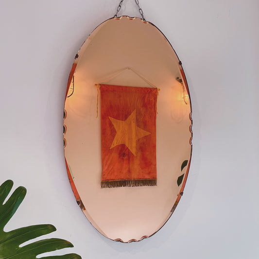 Oval art deco mirror with peachy pink tint
