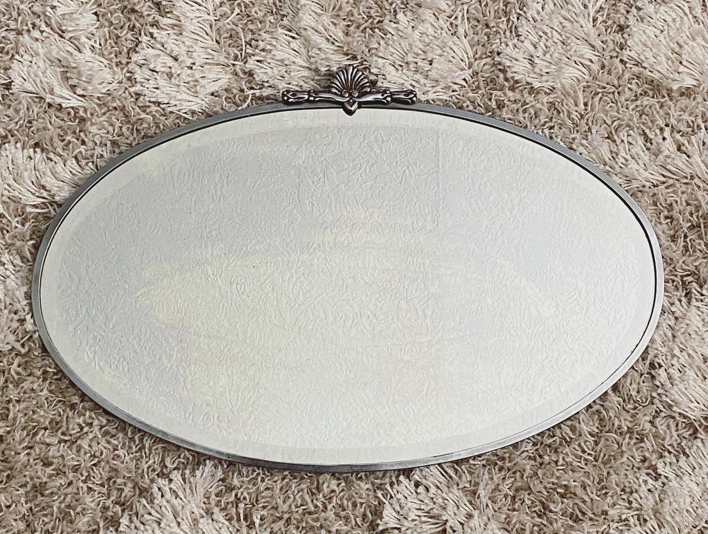 Art Deco beveled mirror with metal frame and decorative topper